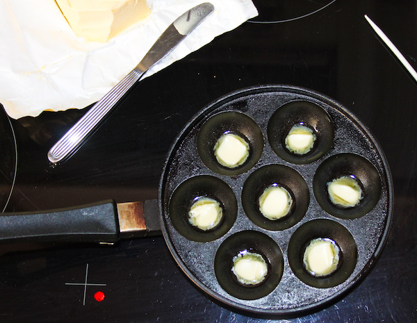 烹饪Æbleskiver前润滑锅里融化黄油